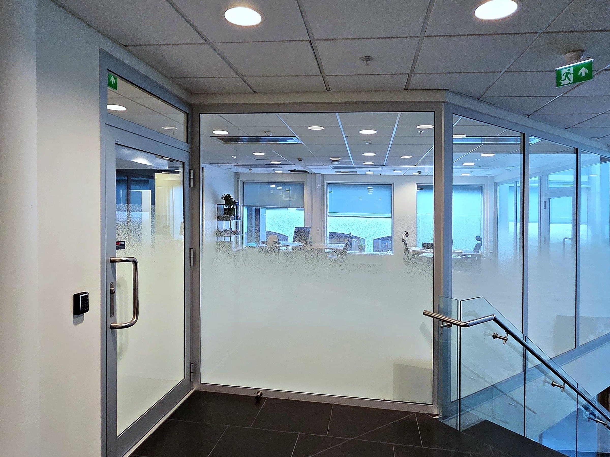 Inngangen til kontoret med glassdør og glassvegg ved trappen